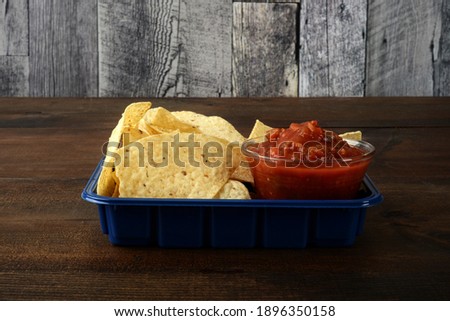 nacho chips with spicy salsa in blue tray
