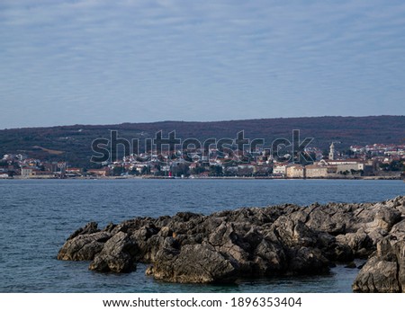 Typical croatian rocky coastline with small town Krk in the background, perfect place for relaxation and leisure