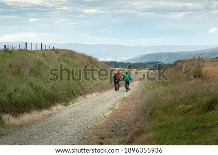 Three people cycling the Otago Central Rail Trail with the mountains in the distance, South Island, New Zealand