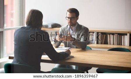 Serious businessman discussing contract details or finding problem solution with skilled financial advisor in modern office. Two successful male partners negotiation project ideas in boardroom. Royalty-Free Stock Photo #1896359467