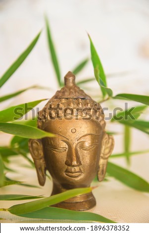 Buddha head and green bamboo on light background. Vertical pictur