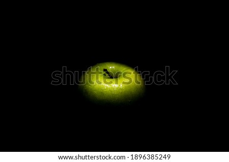 Green apple with small water drops on a black background