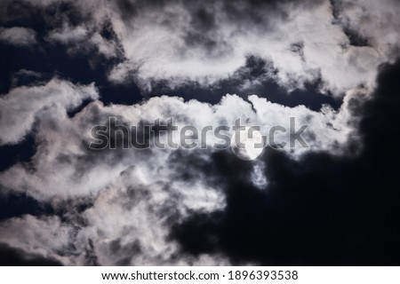 Full moon over the clouds in the night sky. Mysterious picture of the moon