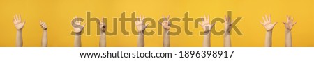 Child's raised up hands and fingers showing numbers from 6 to 10 isolated on yellow background. Royalty-Free Stock Photo #1896398917