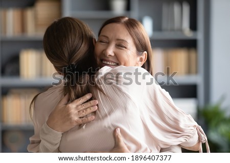 Close up smiling loving mature mother embracing grownup daughter, standing at home, family enjoying tender moment, young woman and happy elderly mum cuddling, expressing support and care Royalty-Free Stock Photo #1896407377