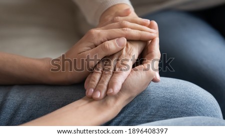Close up caring grown up daughter touching mature mother hand, comforting and calming, expressing love and support, young woman and elderly mum holding hands, two generations trusted relations Royalty-Free Stock Photo #1896408397