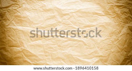 Thin, crumpled paper of light yellow, beige, gold color. A clean sheet of yellowed parchment in Sepia with a darkening at the edge of the sheet.                
