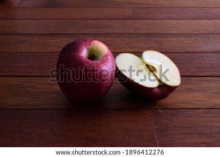 Red apple and half cut apple isolated on wooden table, closeup