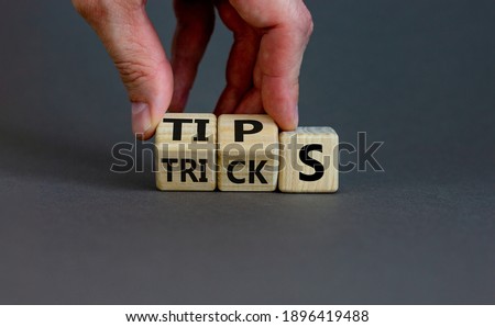 Tips and tricks symbol. Businessman turns cubes and changes the word 'tricks' to 'tips'. Beautiful grey background. Business, tips and tricks concept. Copy space.