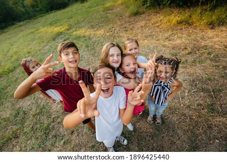 A large group of cheerful children sit on the grass in the Park and smile. Games in a children's camp Royalty-Free Stock Photo #1896425440
