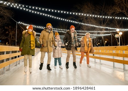 Big happy family riding on the skating rink during the Christmas holidays