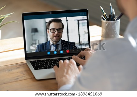 Rear back view young businessman holding video call negotiations meeting with friendly partner or corporate client, discussing common project online using computer application or passing job interview Royalty-Free Stock Photo #1896451069