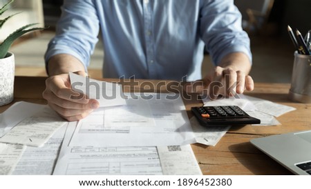 Close up cropped young skilled man analyzing utilities household bills or taxes, calculating domestic expenses, planning monthly budget or mandatory payments, financial paperwork economy concept. Royalty-Free Stock Photo #1896452380