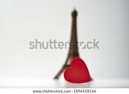 	
Red wooden heart in front of little Eiffel Tower on the light background