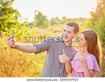 Couple taking photo of themselves with smart phone on romantic picnic date