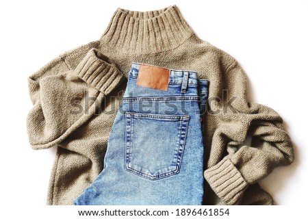 Top view flat lay composition fashion photography. Brown woolen sweater and trendy blue jeans pants. Online clothes shopping