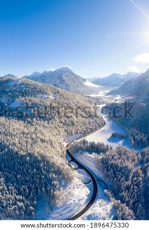 vertical format winter picture with road to the village of heiterwang in tyrol with wooded mountains and a lot of snow