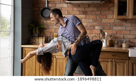 Wide banner panoramic view of overjoyed young Caucasian man and woman have fun dancing in modern kitchen at home. Happy millennial coupler tenants or renters celebrate moving or relocation together.
