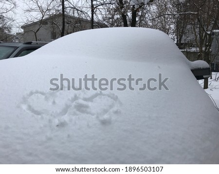 A picture of two hearts drawn by fingers on the car in the winter. front trunk decorated with shape of two hearts. Romantic drawings on the snow surface on the car.