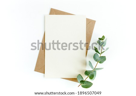 Mockup invitation, blank greeting card and green leaves eucalyptus. Flat lay, top view. Royalty-Free Stock Photo #1896507049