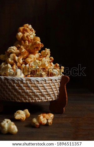 selective focus of pile of popcorn in a wooden wicker bowl with dark background