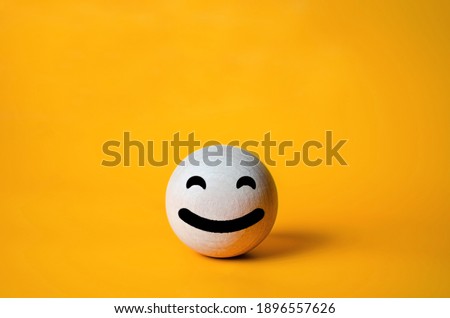 Smile face on wooden ball with orange background. Positive mood. Copy space.Good emotion.