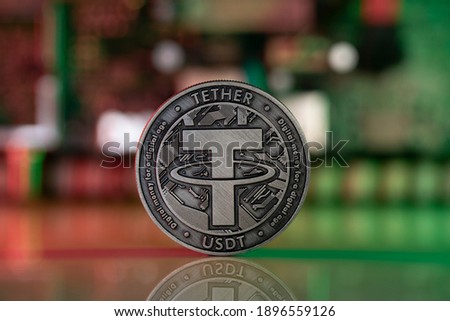 Tether USDT cryptocurrency physical coin placed on reflective surface with microscheme in the background and lit with red and green lights. Royalty-Free Stock Photo #1896559126