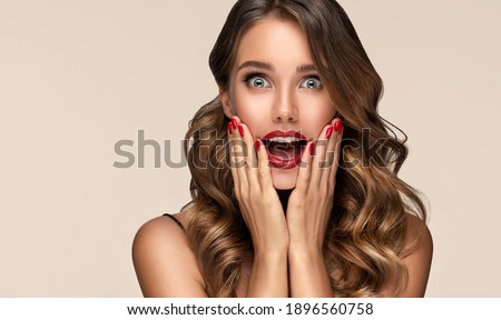 Beautiful shocked and surprised woman screaming .Beauty female with wavy hairstyle. Curly hair girl amazed . Expressive facial expressions . Red nails manicure.Beauty , cosmetic and makeup