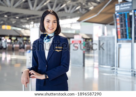 Portrait of beautiful Caucasian flight attendant staff smiling and looking at camera with confidence face and happiness in airport terminal. Feeling welcome all customer or passenger to the airplane. Royalty-Free Stock Photo #1896587290