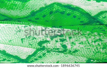 green fabric with snakeskin pattern, background texture of bright green fabric close up. background, texture, pattern