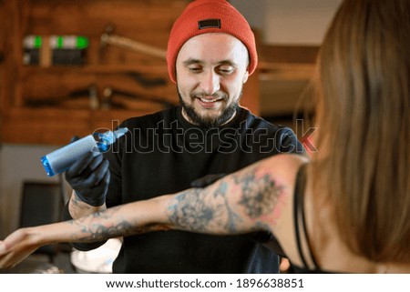 Professional male bearded caucasian tattoo master is working in cozy atmospheric studio
