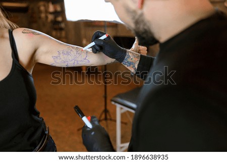 Professional male bearded caucasian tattoo master is working in cozy atmospheric studio