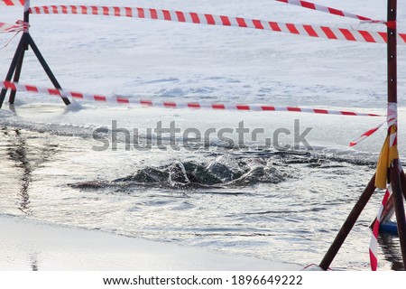 Winter ice diving sport, a trace on the water from a diver in the empty ice hole on a Sunny frosty winter day, healthy lifestyle