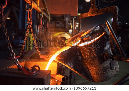Foundry bucket pouring hot molten metal into casting mold. Mettalurgy and steel production. Royalty-Free Stock Photo #1896657211