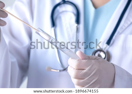 coronavirus COVID-19 test concept. doctor hand with glove holding test tube with patient nasal secretion cotton swab sample for corona virus infection PCR test during pandemic in hospital laboratory Royalty-Free Stock Photo #1896674155