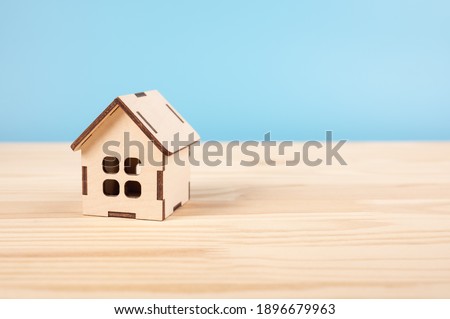 Toy house on wooden table on blue baclground. Mortgage property insurance dream home concept. copy space. House, insurance and mortgage, buing and rent concept.