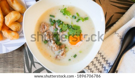 Chinese style porridge or porridge and fried dough stick or fried dough stick or donut or fried bread placed on a wooden table. Thai street food is called "porridge" and "Patongo".
