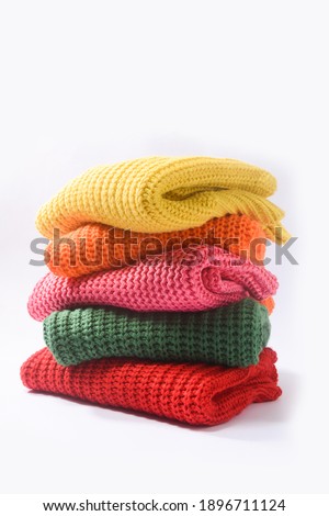 folded and stacked sweaters on white background

