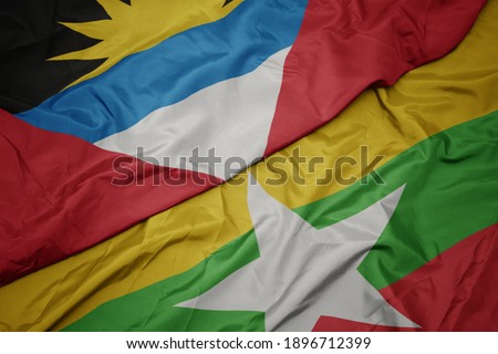 waving colorful flag of myanmar and national flag of antigua and barbuda. macro