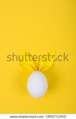 Egg with paper ears in the shape of an Easter bunny. Happy Easter Concept Card Postaer Background. Studio Photo