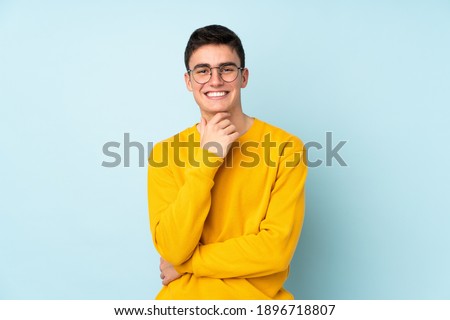 Teenager caucasian handsome man isolated on purple background with glasses and smiling Royalty-Free Stock Photo #1896718807