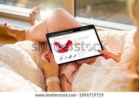 Woman shopping for new high heel shoes online on tablet at home