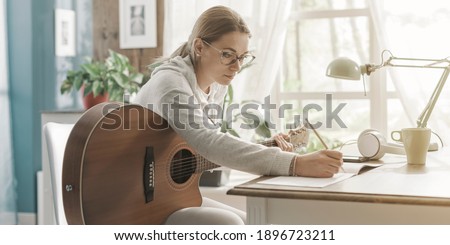 Young creative woman playing guitar at home and composing music Royalty-Free Stock Photo #1896723211