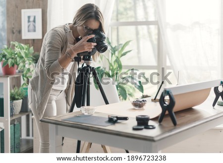Young professional photographer shooting at home, she is taking pictures of food