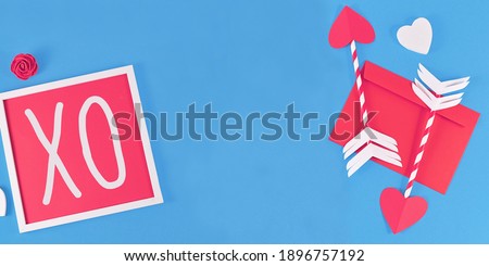 Banner with Valentine's Day composition with picture frame with text 'XO', cupid love arrows, letter, and hearts on blue background