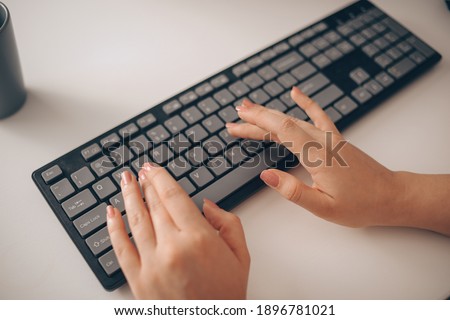 English keyboard, beautiful gentle female hands are typing. Work as a keyword or copywriter.