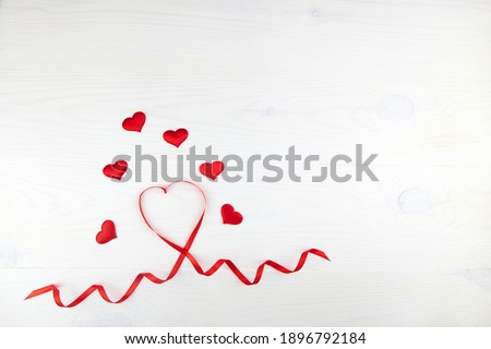 Valentine day greeting card. Red heart-shaped ribbon on a white wooden background.