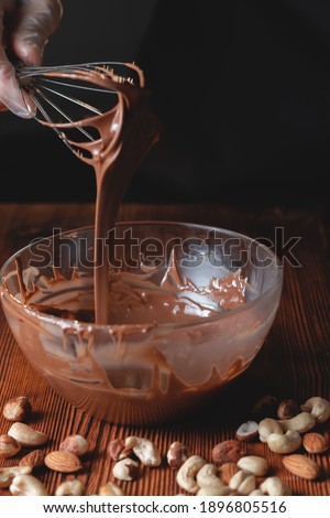 Picture of whisk with chocolate for cake preparation, sweet cake glaze home made process with cocoa melt together to create a glaze for sweet cake and chocolate, close up