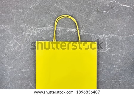 Yellow paper bag on gray stone background. Springtime shopping