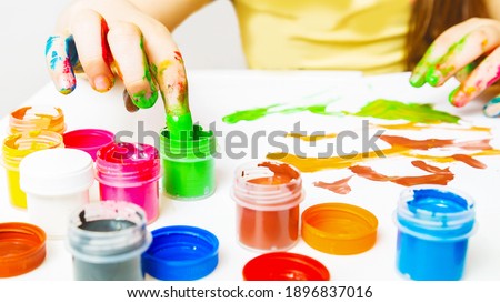 children's creativity. girl painting picture draws with fingers on white background